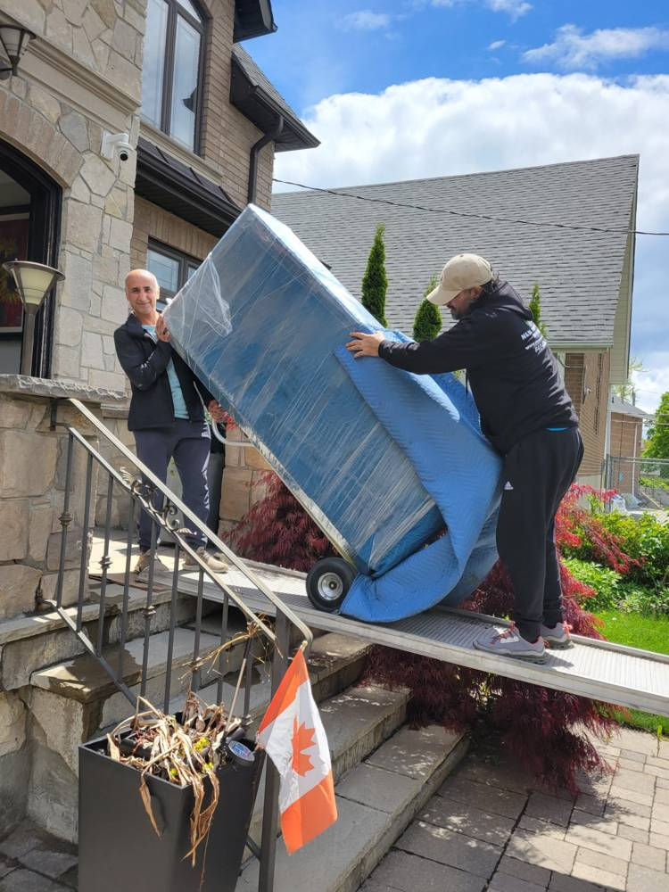 Movers carrying furniture down front steps during a house move in East York